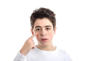 kaukasischer Junge mit glatter Haut, der den Zeigefinger auf sein Auge zeigt foto