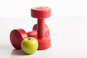 rotes Hantelgewicht mit grünem Apfel foto