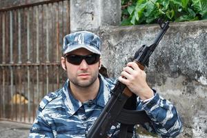 Porträt des militärischen kaukasischen Mannes in der städtischen Kriegsführung, die Gewehr hält
