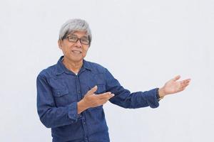 Der asiatische Senior im Denim-Casual-Stil präsentiert etwas Isoliertes auf weißem Hintergrund mit Kopierraum. foto