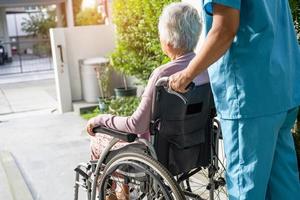 Pflegekraft hilft und pflegt asiatische Senioren oder ältere Frauen, die im Rollstuhl auf der Rampe im Pflegekrankenhaus sitzen, gesundes, starkes medizinisches Konzept foto