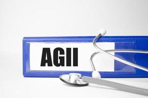 Agii-Wort auf blauem Aktenordner und Stethoskop auf weißem Hintergrund foto