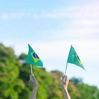 Hand, die Brasilien-Flagge auf Hintergrund des blauen Himmels hält. september unabhängigkeitstag und fröhliche feierkonzepte foto