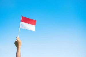 Hand, die Indonesien-Flagge auf Hintergrund des blauen Himmels hält. indonesischer unabhängigkeitstag, nationalfeiertag und fröhliche feierkonzepte foto