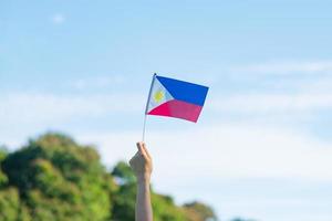 Hand, die Philippinen-Flagge auf Naturhintergrund hält. 12. juni des unabhängigkeitstages und fröhliche feierkonzepte foto