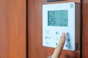 Hand mit Fernbedienung zum Einstellen der Klimaanlage im Zimmer des Hotels oder zu Hause foto