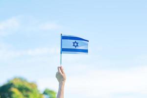 Hand, die Israel-Flagge auf Naturhintergrund hält. israelischer unabhängigkeitstag und fröhliche feierkonzepte foto