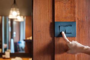 Finger ein- oder ausschalten am Lichtschalter an der Wand zu Hause. Energiespar-, Strom-, Elektro- und Lifestyle-Konzepte foto