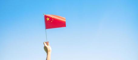 Hand, die China-Flagge auf Hintergrund des blauen Himmels hält. nationaltag der volksrepublik china, öffentlicher nationalfeiertag und fröhliche feierkonzepte foto