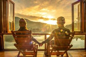 glückliches junges paar, das den seeblick im café am morgensonnenaufgang beobachtet, thailändisches dorf ban rak, provinz mae hong son, thailand. reisen, zusammen und romantisches konzept foto