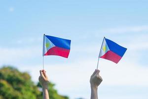 Hand, die Philippinen-Flagge auf Naturhintergrund hält. 12. juni des unabhängigkeitstages und fröhliche feierkonzepte foto