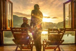 glückliches junges paar, das den seeblick im café am morgensonnenaufgang beobachtet, thailändisches dorf ban rak, provinz mae hong son, thailand. reisen, zusammen und romantisches konzept foto