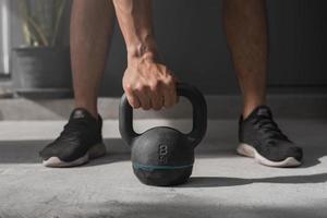 Kettlebell auf dem Boden. Nahaufnahme einer muskulösen Hand, die eine Kettlebell hält. foto