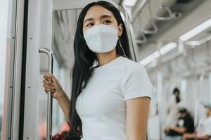 asiatische frau, die schutzmaske in einem zug trägt. Frau mit chirurgischer Schutzmaske in einem öffentlichen Verkehrsmittel. neues normales Konzept. foto