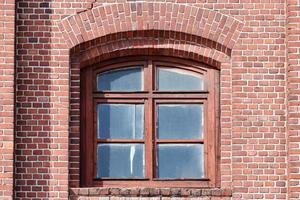 Ein gewölbtes Glasfenster an der alten roten Backsteinmauer foto