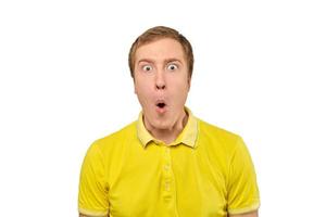 überraschter junger Mann mit lustigem Gesichtsausdruck im gelben T-Shirt, weißer isolierter Hintergrund foto