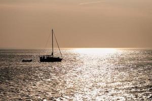 Zwei Segelboote Silhouetten auf dem Hintergrund eines wunderschönen Sonnenuntergangs mit Reflexion in ruhigem Meerwasser foto
