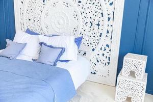 Wunderschönes, klassisches, sauberes Luxus-Schlafzimmer in weißer und tiefblauer Farbe mit Kingsize-Bett und schicken geschnitzten Möbeln. Helles, modernes, stilvolles Schlafzimmer und Wohnzimmer im minimalistischen Stil.