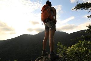 Frau Backpacker auf Berggipfel genießen die Aussicht foto