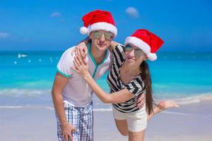 Porträt des jungen Paares in den Weihnachtsmützen genießen Strandurlaub