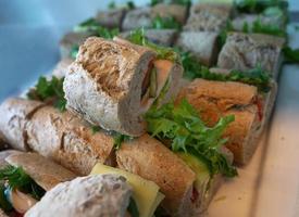 Nahaufnahme Stapel Vollkornbrot gefüllt mit Schinken und Käseaufschnitt, Gurken und frischem Gemüse für die Tapete foto