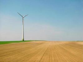 einzelne moderne turbine, die auf dem feld steht, mit gelbem farbzugang mit kopierraum foto