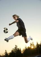 Action-Aufnahme eines Fußballmädchens, das einen Ball in der Luft tritt foto