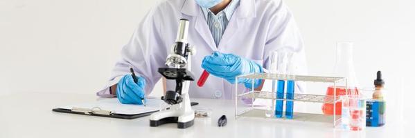 wissenschaftler forschen im labor in weißem laborkittel, handschuhe analysieren, betrachten reagenzglasproben, biotechnologiekonzept