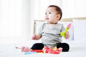 hübsches Baby spielt Babyspielzeug auf dem Bett. foto