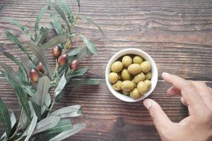 pflücken Sie frische Oliven von Hand in einem Behälter auf dem Tisch.