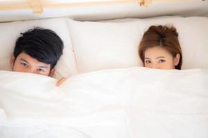 Schönes junges asiatisches Paar lächelt lieblich versteckte Decke im Bett zusammen, Mann und Frau Spaß und glückliche liegende Decke, Familiengefühl romantisch und Liebe, Lifestyle-Konzept, Draufsicht. foto