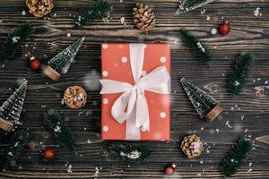 weihnachtsfeiertagskomposition mit roter geschenkbox und tagdekoration auf holzhintergrund, neujahr und weihnachten oder jahrestag mit geschenken auf holztisch in der saison, draufsicht oder flachlage.