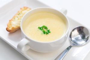 köstliche Maissuppe in einer weißen Schüssel, serviert mit Brot. foto
