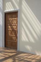 Seitenansicht der Holztür in mastixfarbener Zementwand mit Sonnenlicht und Schatten der Dachkonstruktion auf der Oberfläche der Holzbodenfliesen innerhalb der Hausbaustelle im vertikalen Rahmen foto