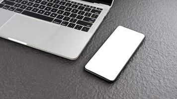 nahaufnahme und hochwinkelansicht des smartphone-modells mit laptop auf grauer tischplatte, leeres weißes bildschirm-handy für text- und grafikanzeigemontage foto