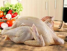 rohes Hähnchen ganz, Kochzubereitung, isoliert auf Küchenhintergrund foto