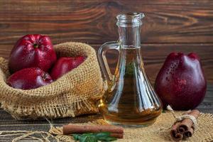 Apfelessig und rote Äpfel auf einem dunklen, hölzernen Hintergrund. selektiver Fokus. fermentiertes Produkt. gesundes Essen. foto