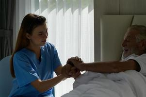 Der Arzt spricht mit einem älteren Patienten, der allein in einem speziellen Krankenhauszimmer liegt. foto