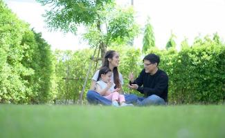 asiatische familie mit vater, mutter und tochter, die sich glücklich im garten des hauses amüsieren foto