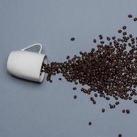 Kaffeebohnen und weiße Tasse auf farbigem Hintergrund foto