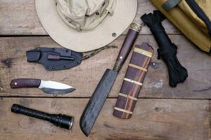 Ein Messer mit Überlebensausrüstung im Wald auf einem alten Holzboden foto