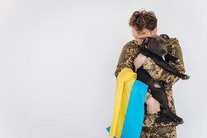 ukrainischer soldat in militäruniform mit gelber und blauer flagge hält einen hund in seinen armen auf weißem hintergrund foto