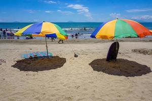 bunter Regenschirm am Sandstrand unter blauem Himmel. sommerferien reisen. tropische urlaubsreise. kostenloses Foto