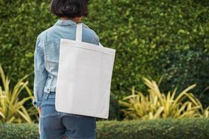 junges Mädchen mit weißer Stofftasche im Park foto