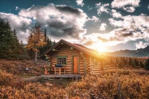 Sonnenaufgang auf Holzhütte im Herbstwald im Assiniboine Provincial Park foto