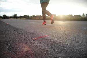 Selektiver Fokus auf der Asphaltstraße mit bewegungsunscharfem Athleten, der im Hintergrund joggt foto