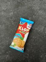 sukoharjo - 8. juni 2022 - snack namens marke klop cracker, kokosgeschmack, zementbodenhintergrund, süßer keks mit kokosgeschmack foto