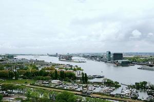 amsterdam, die niederlande - 28. april 2019 stadtansicht zum zentralen teil der stadt, fähre und kanal von oben an bewölktem typisch holländischem tag. foto