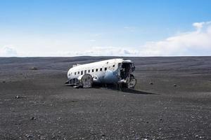 Verlassenes beschädigtes Flugzeugwrack am schwarzen Sandstrand in Solheimasandur gegen den Himmel foto