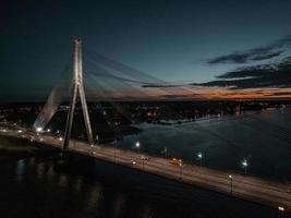 luftpanoramablick auf die rigaer brücke über den fluss daugava bei nacht. Schrägseilbrücke in Riga, Lettland bei Nacht. foto